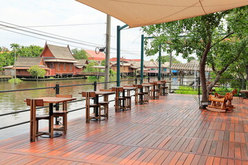 View of wooden stylish outdoor waterside cafe with couple seat design idea. Wooden tables and chairs simplistic. Empty restaurant cafe.