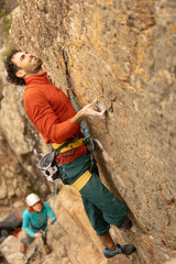 Person climbing in high mountains with yellow jacket rope and helmet in nature, confidence and risk, safety