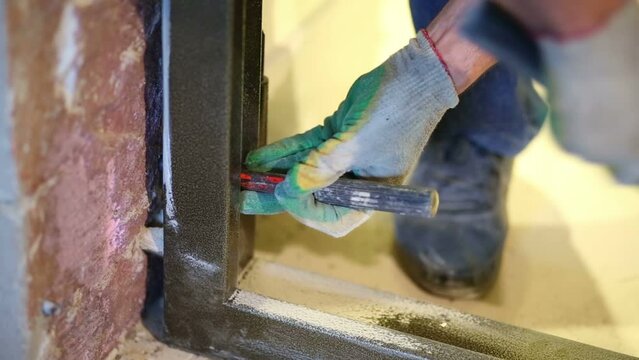 Hands of worker hammering metal sleeve for install metal door
