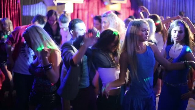 Eighteen young people have fun and dance at party in night club