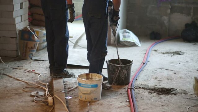 Legs of two workers mixing cement mortar with mixer