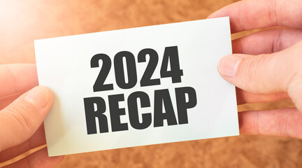 2024 RECAP word inscription on white card paper sheet in hands of a businessman. recap concept. red...