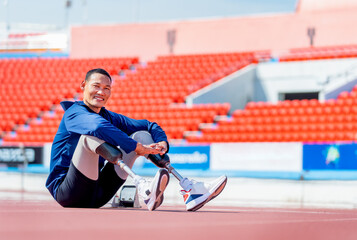 Sport man athlete prosthesis legs sit on the track and look at camera with smiling after exercise...