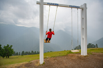 Playground Escapade: Man in Orange T-Shirt on the Swing