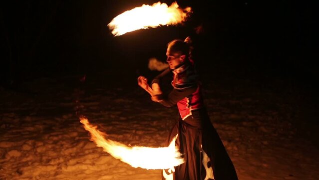 Performance of man in samurai garb with fire balls on chains