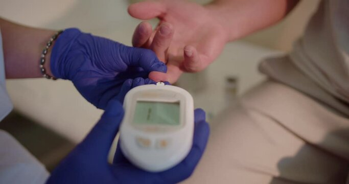 Close up video of doctor using glucometer to check the blood sugar level of patient at the hospital laboratory.