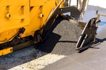 As part of construction of highway machinery lays fresh bitumen asphalt on top gravel base