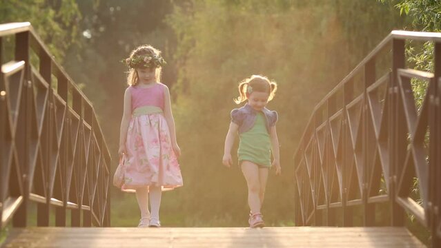 Little girl teaches dance with another girl on bridge in park
