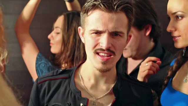 Mustached man in jacket dancing on a party with young people