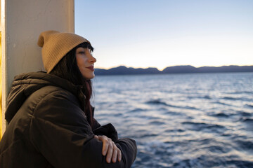 tourist woman leaning out of the window of a boat watching the sunset