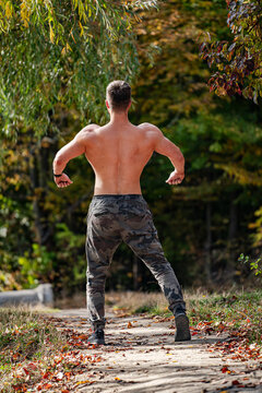 Macho bodybuilding man. Outdoor shirtless muscular man posing.