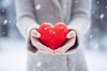 woman hand hold red heart in snowy winter day