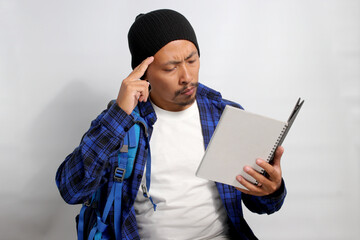 A pensive young Asian student, dressed in a beanie hat and casual shirt, carrying a backpack and...