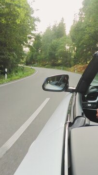 convertable car in sunny nature on a bright summer day. wide angle pursuit shot - vertical video for reels and story