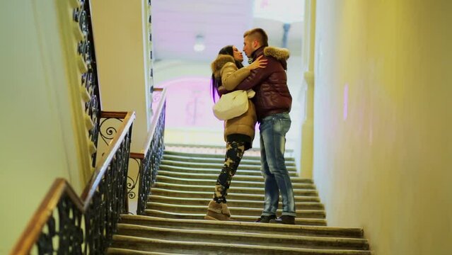 Young couple hug and kiss on staircase in trade center