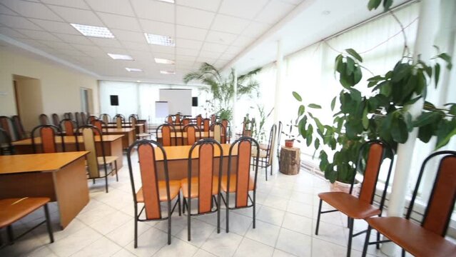 Interior of conference hall with chairs, tables and plants 