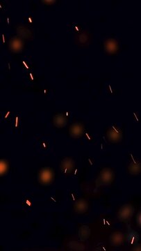 ultra slow motion high speed shot of fire flames and glowing ash particles on black background - vertical video for reel and story