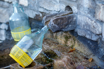 collecting safe spring mineral water from source in mountain for human consumption with glass bottle