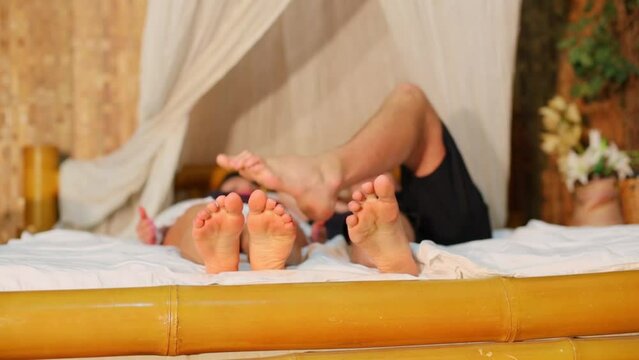couple move their feet while lay on bed and man touch woman