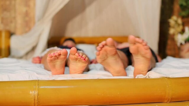 Young couple move their feet and fingers while lay on bed