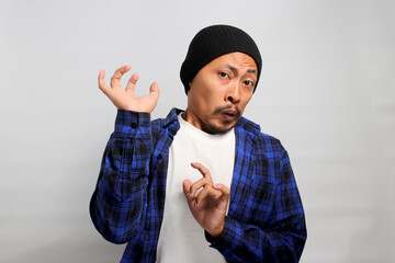 Ew. It's so gross. Displeased young Asian man, dressed in a beanie hat and casual shirt, wears a...
