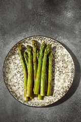 Fresh green asparagus. Cooking healthy food on a beautiful colorful handmade plate. Bunches of green asparagus, top view. Image