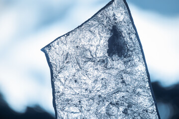 Transparent ice shard macro photo over blurred blue background