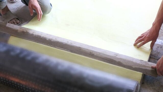 Hand of men cutting sound insulation for floor in room