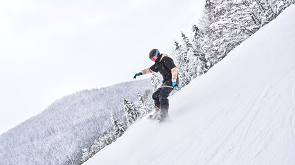 Making some moves. Male snowboarder is riding from the snowy hill while making some extreme moves - Powered by Adobe