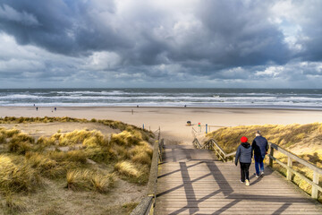 A couple starting a beach walk on a stormy day in January on Kijkduin Beach near The Hague.