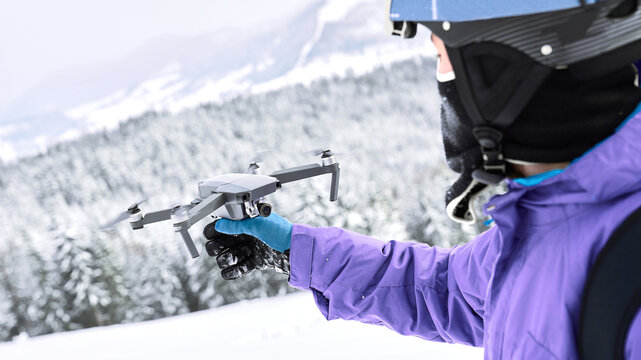 Close up shoot with man in blue gloves that getting start to launch his flying drone to make some aerial view pictures on it from the winter mountain top
