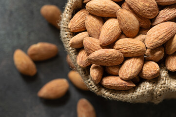 Delicious sweet almonds in wooden bowl on rustic background, roasted almond nut, healthy food