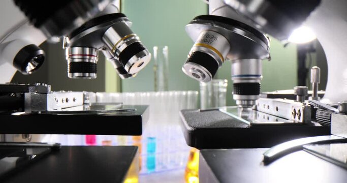Modern medical research laboratory with many microscopes and test tubes with colored liquids in test tubes on table