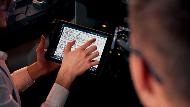 pilots in the cockpit of the plane near the control panel with a tablet in their hands discuss the route before the start of the flight simulator