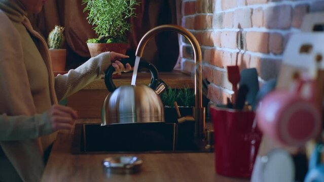 Amazing kitchen design rustic stile capturing video closeup lady take the kettle and add some water tap to boil water for a hot drink