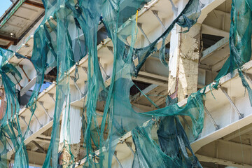 Protective mesh on scaffolding torn by hurricane wind. Background with selective focus