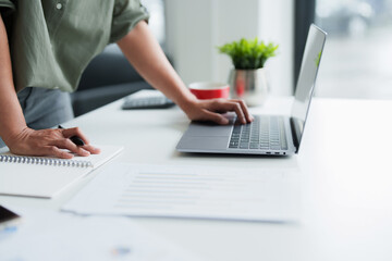 Businesswoman using laptop with technology to typing and working about calculation tax in office