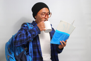 Young Asian student, dressed in casual clothes and a beanie hat, stands against a white background,...