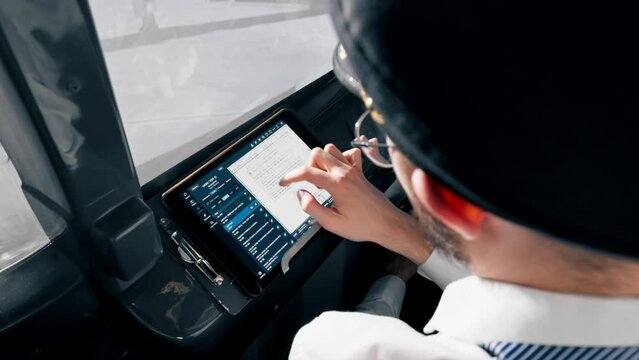 the pilot holds a tablet in his hands looks at the flight route and chooses the landing place of the plane close-up