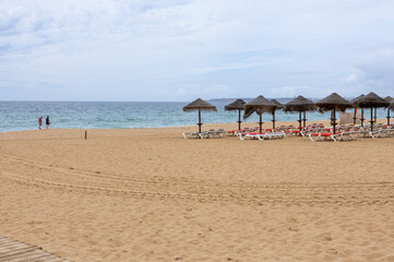 Beach with empty sunbeds and umbrellas on a beach in the Algarve, Portugal