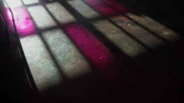 Window shadow drop on a concrete floor in loft interior. Colourful pink glass. Person walks through. 