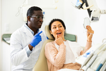 Dentist patient looks in the mirror at a new tooth after surgery
