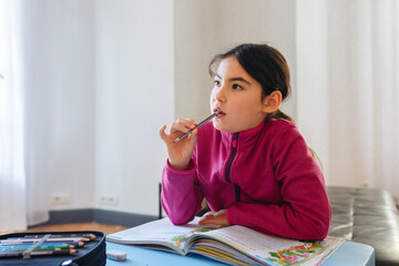 portrait of thoughtful girl sitting at the desk doing homework