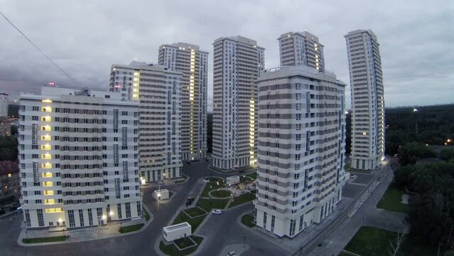 Housing estate stands near trees against cloudy sky at evening
