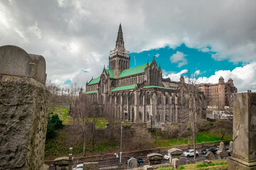 Obraz premium Big Glasgow cathedral on a spring day looking from above at the location of Glasgow Necropolis. Cloudy day and a big victorian cathedral church