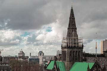 Big Glasgow cathedral on a spring day looking from above at the location of Glasgow Necropolis. Cloudy day and a big victorian cathedral church. Detail of the tower under construction