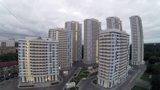 Housing estate stands near trees against cloudy sky at evening