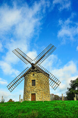 front view, medium distance of, a windmill in Caisdo Pescador, Italy, against blue sky with white clouds