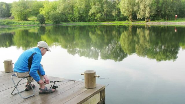 Boy throws a fishing rod in the pond at summer day. Time lapse.