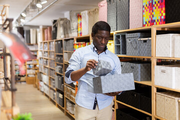 Adult african american man visiting home decor store in search of functional storage boxes